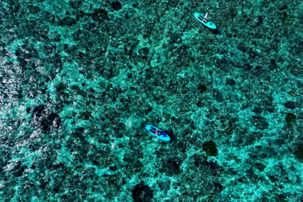 Deux participants pratiquant le paddle dans les eaux turquoise de Molana Island pendant la Wild Banda Sea Expedition de Konjo, en Indonésie.